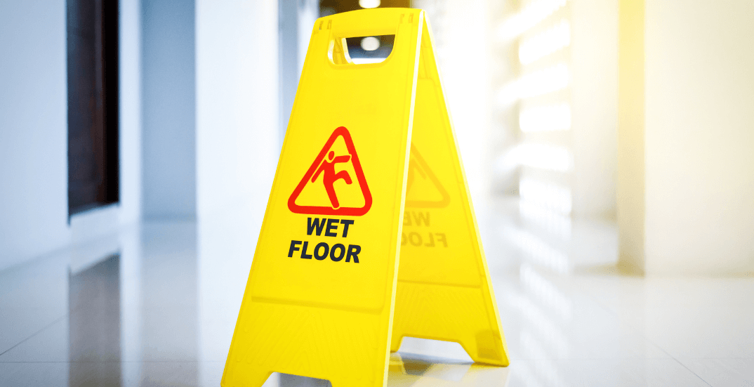 Hotel lobby with 'Caution: Wet Floor' sign - corena law